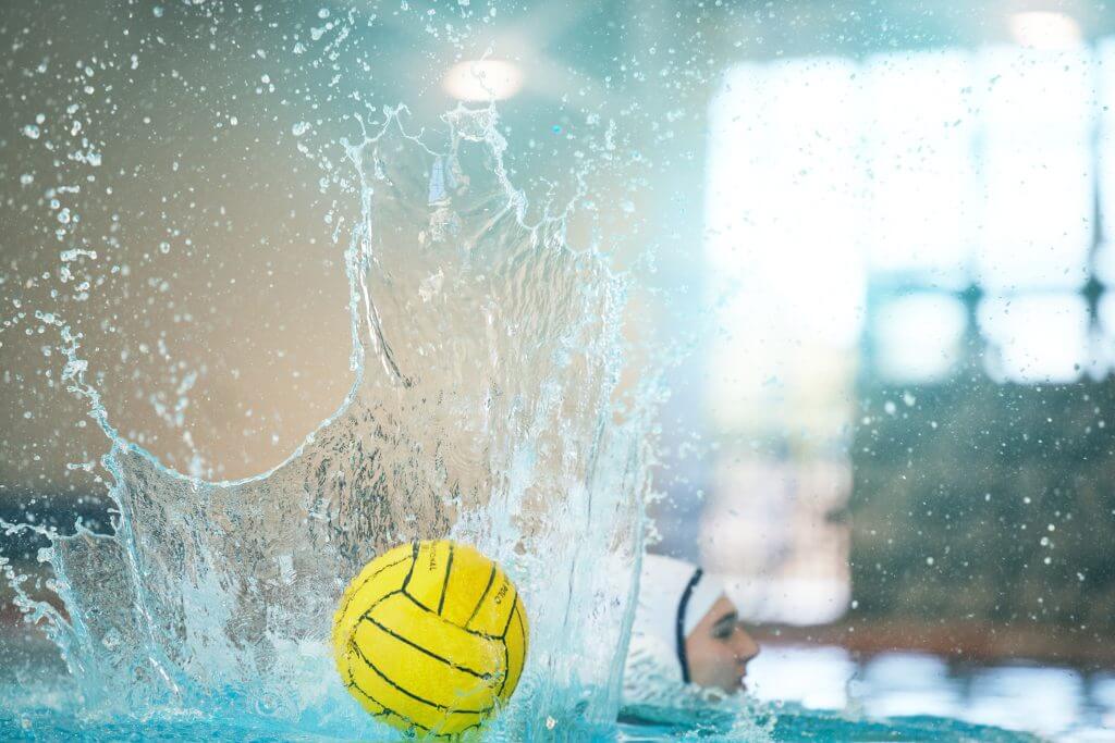 Water Polo Ball Splash with Athlete in Swimming Pool