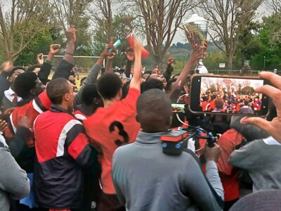 Maritzburg College captain KG Matshoge hoists the Cowie Cup, surrounded by the Red, Black and White's supporters.